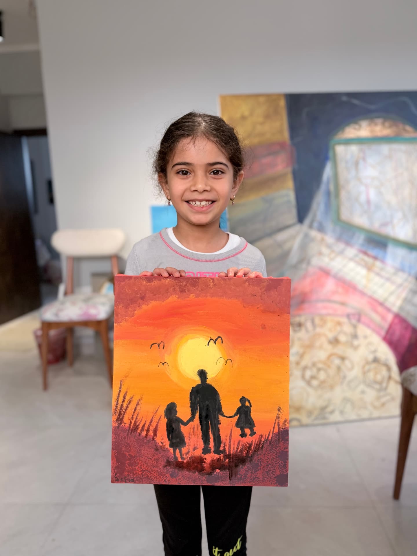 Young student holding a sunset painting made in class