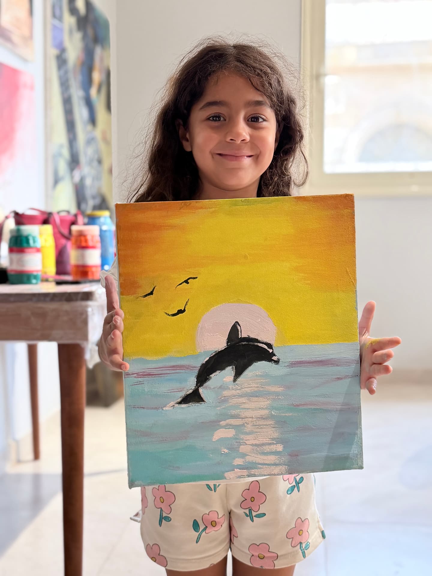 Young student holding a dolphin painting made in class