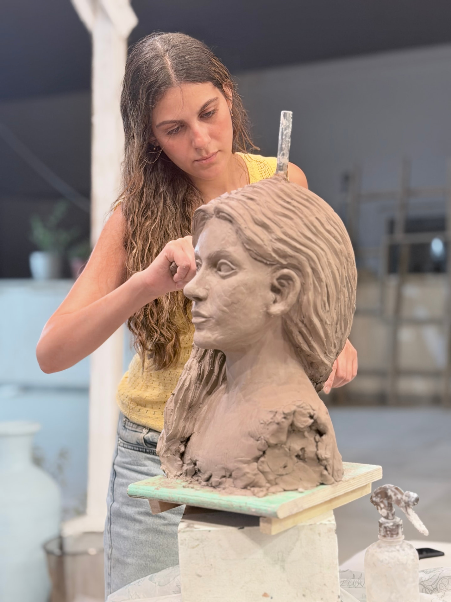 Student sculpting a clay portrait bust